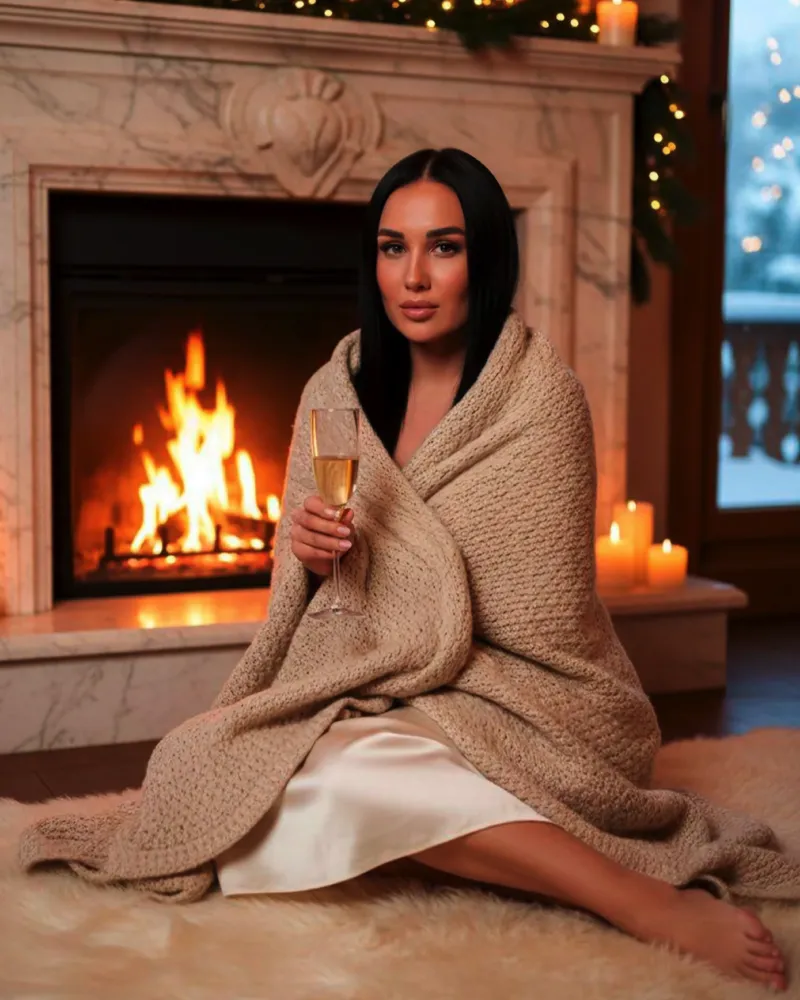 Женщина у камина в пледе с бокалом шампанского, свечи и уют